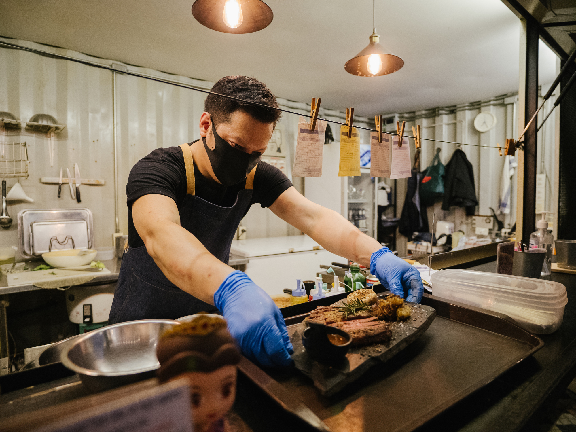 Chef with gloves and mask serving food after safely reopening after COVID quarantine.